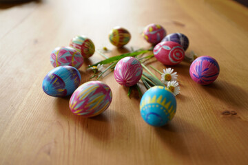 Colorful Easter Eggs on Wooden Table with Daisy Flowers Celebrating Spring Holiday Season and Festive Decorations for Easter Sunday