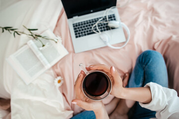 Morning coffee and remote work on bed with laptop and book