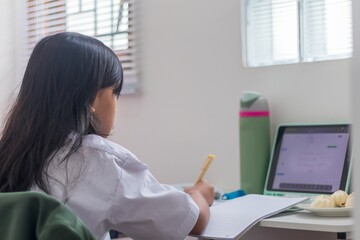 An Asian student girl studying online from home using tablet computer