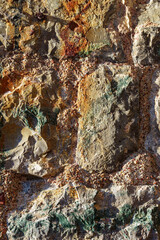 natural old stone as a background, illuminated by contrasting sunlight bright and shadows, rough structure and weathered