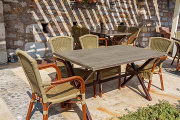 cozy outdoor cafe or restaurant located on embankment of Petrovac city, Montenegro, tables and chairs against the background of a stone wall of an old building