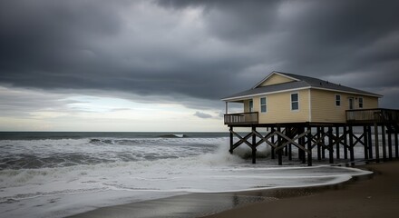 Beach house on stilts facing stormy ocean with dark clouds and crashing waves during a hurricane.