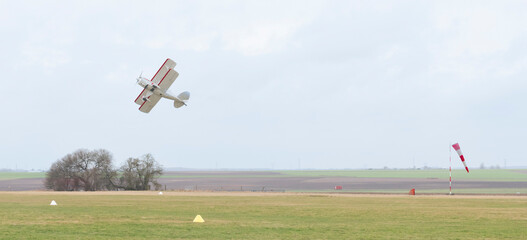 Avion biplan volant près du sol au dessus de la piste d'atterrissage. © Valentin