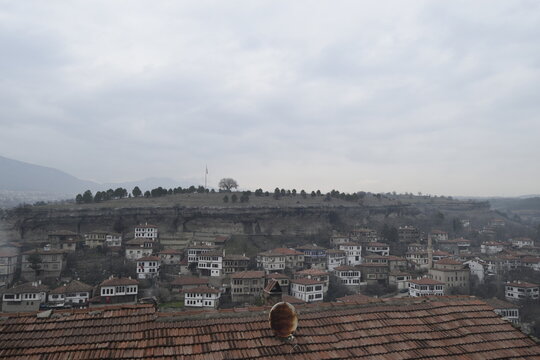 View of traditional white-walled houses with red-tiled roofs cascading down a hillside under a cloudy sky, Safranbolu, Karab&Atilde;&frac14;k, T&Atilde;&frac14;rkiye.