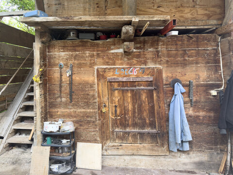 View of a rustic wooden structure with weathered planks and a sturdy door, tools hanging nearby, evoking a sense of history and rural life, Posof, Ardahan, T&Atilde;&frac14;rkiye.