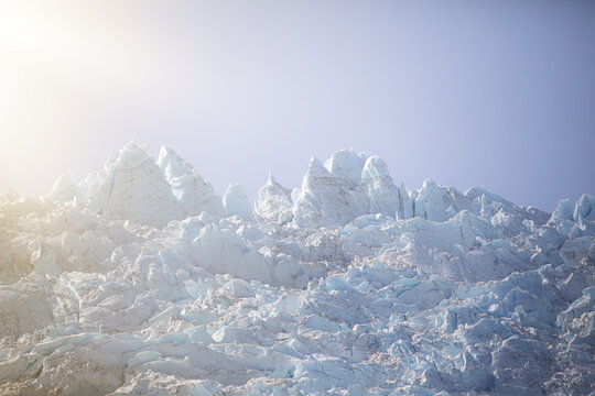View of Aialik Glacier's jagged, icy peaks reach towards the pale blue sky, a frozen landscape sculpted by time and weather of Kenai Fjords National Park, Seward, Alaska, United States.
