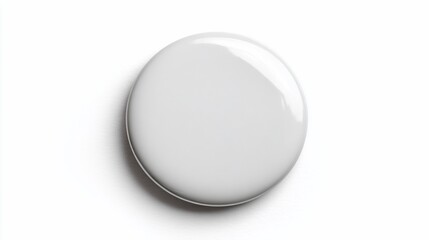Single white blank button pin lies on flat white surface