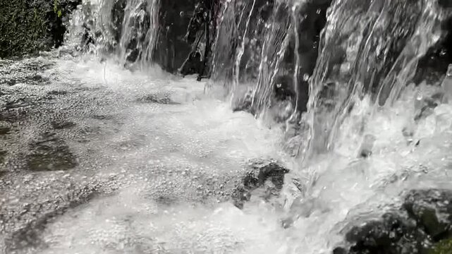 Cascading Rapids: A close-up capture of water cascading and flowing rapidly over textured rocks, emphasizing the dynamism and beauty of natural water forms.