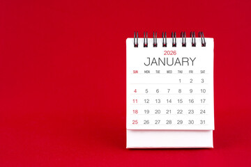 White desk calendar for January 2026 on red color background.