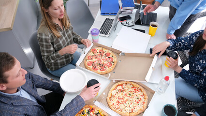 Coffee break. Company employees eat pizza in the office. A break at work. A delicious snack. A group of people are enjoying pizza in the office kitchen