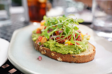 Gourmet avocado toast on artisinal bread with pickled mango and microgreens