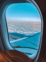 Fototapeta premium Airplane wing and cloudscape view from passenger window during flight.
