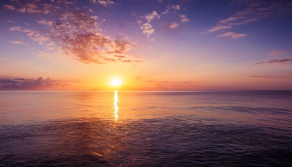 Fototapeta premium b roll of the sun slowly sinking into the sea casting long golden reflections and painting the sky with hues of orange pink and purple