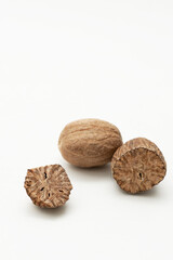 Close-up of whole and halved nutmeg seeds on a white background, aromatic spice used in cooking and baking