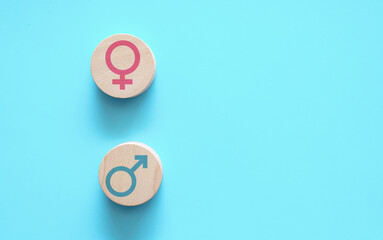 Male and female gender symbols on wooden tokens against blue background. Gender equality, diversity concept, women's rights, feminism, sexual identity