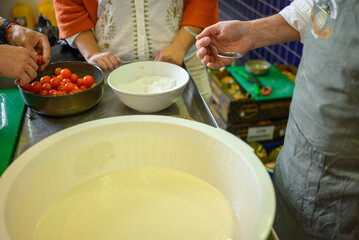 Cooking class in session with fresh produce on a steel counter.