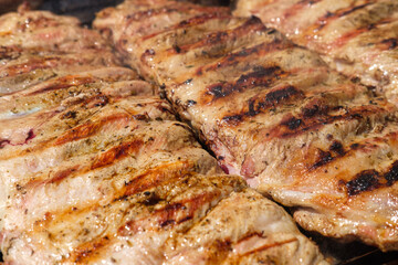 Grilled meat sizzling on a hot BBQ grill in summer.