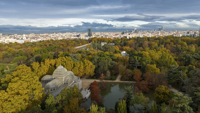 Aerial view of serene Retiro Park with vibrant autumn foliage, Crystal Palace, and tranquil pond, Madrid, Madrid, Spain. - Powered by Adobe