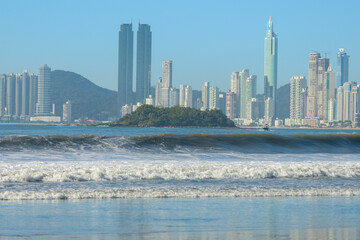 Naklejka premium Surfing in the heart of Brazil’s luxury coast – where ocean waves meet a stunning skyline.