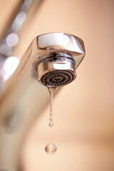 Dripping tap with water droplets inside apartment bathroom. Macro, close up, looking up shot, shallow depth of field, no people