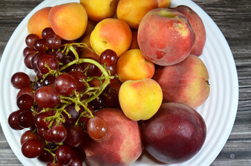 assorted fresh fruits of apricots, peach and red grapes, healthy food concept, summer fruit, peaches, apricot and red grape, selective focus