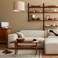 Modern interior of living room with design modular beige sofa, coffee table,  furniture, pendant lamp, shelf, slippers, carpet, decoration and elegant personal accessories in home decor. Template.