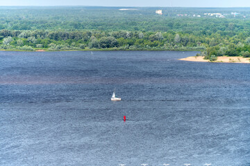 Scenic view of sailboat on volga river, near lush green of Nizhny Novgorod. Vast water body complements serene landscape, with distant visibility under soft daylight