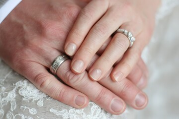 Close-up of clasped hands, wedding rings visible