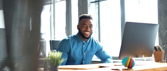 The smiling man working at his modern office desk with a computer.