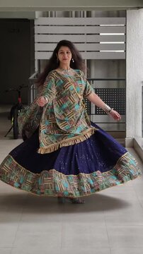 Woman twirling gracefully in a navy blue ghaghra with ajrak print dupatta, showcasing traditional Indian festive attire and cultural elegance during celebrations