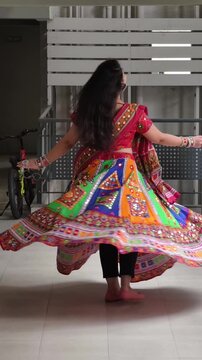 Woman twirling in vibrant mirror work chaniya choli, showcasing traditional Gujarati attire for Navratri and Garba celebrations, highlighting colorful ethnic fashion and cultural heritage.