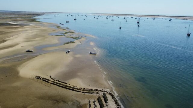 Ria Formosa riverbed at low tide, with shellfish production and yachts anchored in the river in Algarve, Portugal