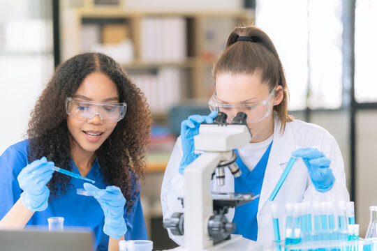 Science concept. Two female doctors are conducting research, studying substances under a microscope in a modern medical laboratory.
