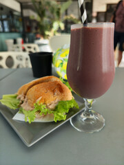 Tuna sandwich with lettuce and a berry smoothie on a grey table, healthy lunch