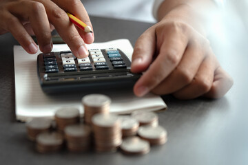 Close-up of hands using a calculator with coins on the table, representing budgeting, cost calculation, and financial planning.