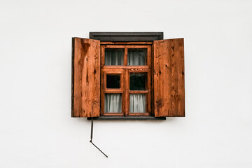 Rustic wooden window with open shutters on white wall