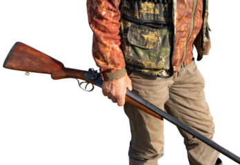 Mature man hunter with gun while walking on field.