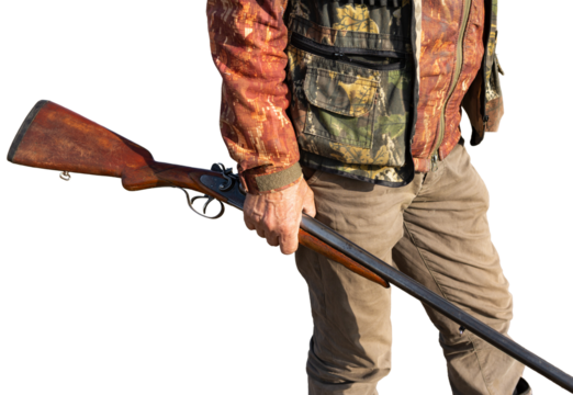 Mature man hunter with gun while walking on field.