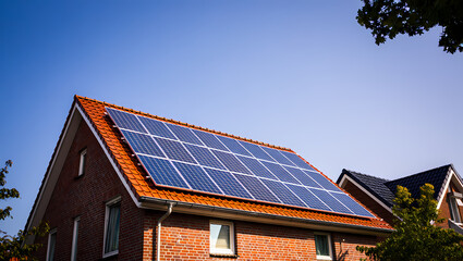 Fototapeta premium Modern Solar Panels on the Red Tiled Roof of a Brick House on a Sunny Day
