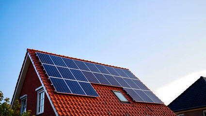 Fototapeta premium Modern Solar Panels on the Red Tiled Roof of a Brick House on a Sunny Day