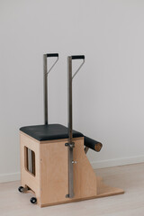 Naklejka premium Pilates reformer chair and combo chair with natural wood details shown in the image. Equipment designed for pilates exercises, stability training, and body toning in gym settings.