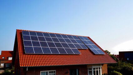Fototapeta premium Modern Solar Panels on the Red Tiled Roof of a Brick House on a Sunny Day
