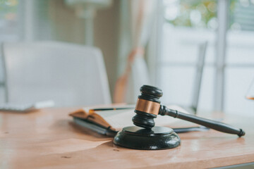 A wooden gavel rests on a stack of documents beside a laptop, symbolizing power and justice.