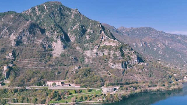 lake Idro and mountain with a road and Rocca d'Anfo buildings at its base on a sunny day in Italy
