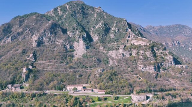 lake Idro and mountain with a road and Rocca d'Anfo buildings at its base on a sunny day in Italy