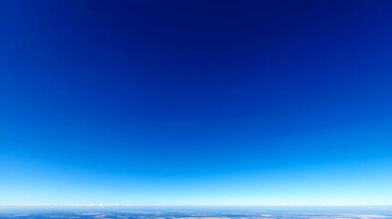 Fototapeta premium Lowangle shot of a vibrant blue sky with a gentle gradient from deep azure at the top to pastel sky blue near the horizon, creating a serene and expansive background with ample copy space on the righ