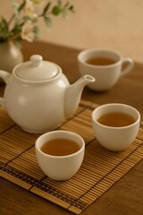Fototapeta premium White Porcelain Teapot and Teacups on Bamboo Mat