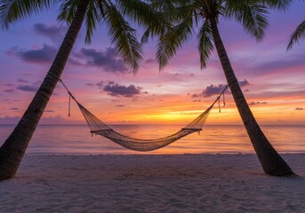 Tranquil beach hammock between palm trees at a vibrant tropical sunset