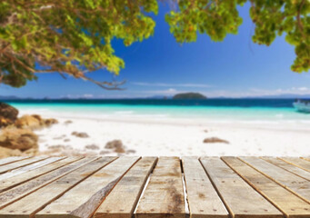 Fototapeta premium Wooden table top on the beach or sea.Party on the beach sunshine time concept.For montage product display or design key visual layout.View of copy space.