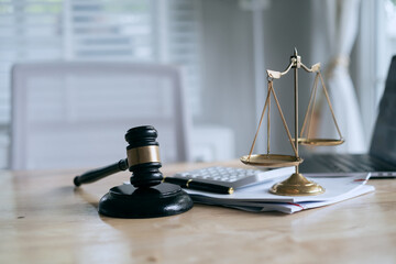 A wooden gavel rests on a stack of documents beside a laptop, symbolizing power and justice.